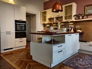 Küche im modernen Landhaussstil, Magnolie Dekor, Arbeitsplatte Dekor Caledonia, Nischenrückwände Ornament rot, Griffe Kupfer antik